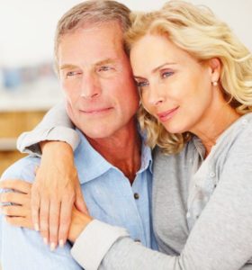 Relaxed mature couple with arms around looking away