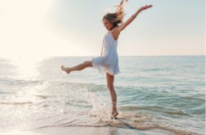 happy woman dancing turning around by sea beach