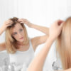 woman with hair loss problem looking in mirror at home